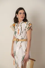 Vestido midi camisero de algodón color natural con estampado de flores, animales y ramas en tonos rojo, marrón, verde y azul. Tiene cuello mao, mangas cortas con volados, bolsillos laterales y cinturón de soga color beige.