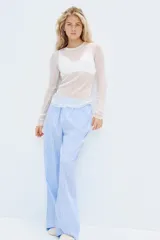 Pantalón de pijama celeste con rayas verticales blancas, de algodón suave, corte relajado, tiro bajo, cintura elástica, cierre decorativo con botones, piernas rectas y bolsillos laterales.