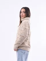 Campera de abrigo de tejido tipo sherpa o borrego, color beige claro con estampado animal print sutil en tonos más oscuros. Tiene cuello alto y cierre frontal.