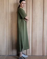 Vestido midi negro con cuello redondo y mangas cortas. Presenta dos bolsillos cuadrados en el pecho y ribetes blancos en cuello, mangas, bolsillos y ruedo.