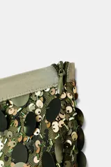 Falda corta de tiro medio, cubierta completamente de lentejuelas redondas de color dorado/verde oliva. Presenta forro interior.