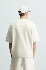 Sudadera relaxed fit color crudo confeccionada en tejido interlock de algodón con elasticidad, cuello redondo, manga corta y bajo acabado en rib.