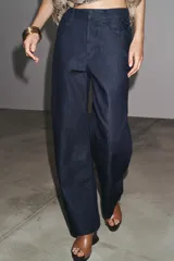 Pantalón de jean azul oscuro, de tiro alto, corte ancho y largo hasta el tobillo.