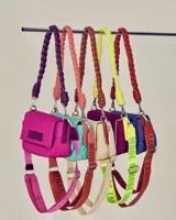 Cartera bandolera fucsia con patrón acolchado y ribete amarillo neón. Tiene asa corta trenzada color verde neón y logo "LAMODE" estampado en amarillo neón.