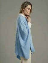 Poncho tejido de punto grueso, color mostaza/mostaza oscuro, con cuello redondo y caída amplia.