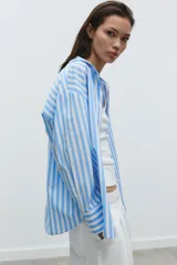 Camisa celeste y blanca a rayas verticales, de popelina, con cuello solapa, escote en pico y mangas largas.