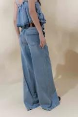 Pantalón de jean color beige, de tiro medio, corte amplio y ruedo acampanado.