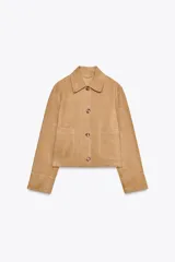 Chaqueta corta de ante color beige, con cuello solapa, manga larga, bolsillos de parche en el delantero y cierre frontal con botones.
