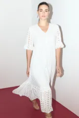 Maxi vestido blanco con bordado calado tipo broderie, escote en V, mangas cortas con volados y corte escalonado en la falda.