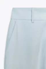 Pantalón celeste de tiro alto con bolsillos delanteros y pernera recta. Cierre frontal con cremallera y botón.