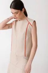 Blusa color ladrillo de lino 100% con cuello redondo y sin mangas. Presenta vivos y pespuntes a contratono en color marrón.