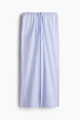 Pantalón de pijama largo de algodón con estampado de rayas verticales celestes y rojas. Tiene cintura elástica con cordón ajustable y corte holgado.