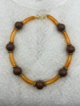 Collar corto con cuentas redondas color lila y cuentas cilíndricas color verde oliva, separadas por anillos dorados.