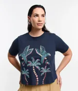 Remera cropped de algodón azul marino, con cuello redondo, mangas cortas y estampa delantera de guacamayas y cocoteros.