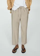 Pantalón fluido color beige, de corte recto y tiro alto, con cintura elástica y cordón ajustable. Presenta bolsillos laterales y diseño jogger.