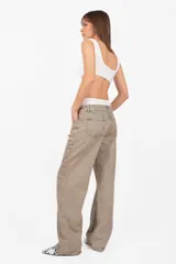 Pantalón de denim corte recto, tiro medio, color arena. Acceso con cierre metálico y botón personalizado. Cintura con cinco presillas, logo estampado en la parte trasera y bolsillos laterales con remaches. Lavado artesanal con matizado color arena. Los tonos pueden variar.