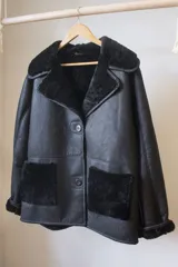 Campera gamulán negra de cuero genuino con cuello, solapas y bolsillos de piel sintética.