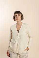 Cardigan tejido con efecto fantasia color crema. Una prenda de silueta amplia y cómoda. Tejido en 100% lana fina sin teñir.