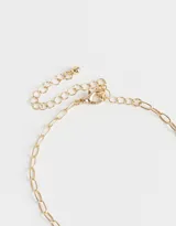 Collar largo dorado con cadena de eslabones y dijes colgantes con forma de trébol de cuatro hojas, estrella y cuenta de cristal.
