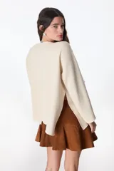 Sweater color crudo con bordado de flores rojas, amarillas y azules.