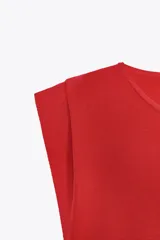 Top negro de punto con cuello redondo, sin mangas y bajo asimétrico con detalle de lazo lateral.