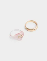 Set de dos anillos, uno dorado liso y otro rosado transparente con forma de corazón y moño dorado.