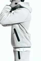 Campera deportiva gris con capucha, cierre frontal y bolsillos laterales con cierre. Confeccionada en tejido funcional DryMove™ que ayuda a absorber el sudor.