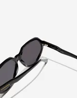 Lentes de sol unisex Hawkers X Paula Echevarría, modelo Retro Eco, con montura geométrica negra y lentes grises.