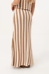 Falda larga tejida a rayas verticales color beige y blanco, con pretina elástica y tajos laterales.