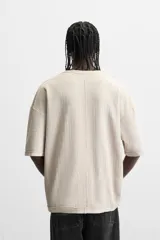 Camiseta color gris verdoso de punto tejido en hilatura de algodón, con cuello redondo, manga corta, efecto lavado y acabados irregulares.