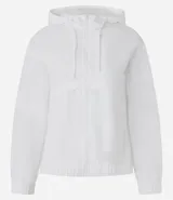 Campera deportiva femenina alargada, con capucha y tecnología cortaviento. Posee cuerda de ajuste en la capucha y cierre delantero por cremallera. Incluye saquito para guardar.