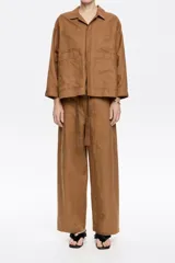 Pantalón blanco de lino y algodón, corte barrel, largo tobillero, con cierre frontal oculto, bolsillos delanteros y traseros, y cinturón de tela a tono.