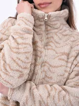Campera de abrigo de tejido tipo sherpa o borrego, color beige claro con estampado animal print sutil en tonos más oscuros. Tiene cuello alto y cierre frontal.