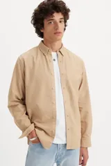 Camisa de manga larga color beige, con cuello abotonado y cierre frontal con botones.