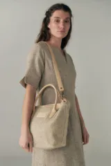 Cartera tipo tote de lana color beige con forro, cierre y asa de cuero regulable.
