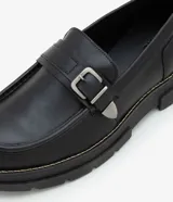 Zapato negro de cuero sintético con punta redonda, detalle de hebilla plateada y suela track.