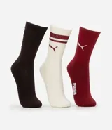 Kit de tres pares de medias deportivas Puma de caña larga. Un par color beige con dos rayas marrones horizontales en la parte superior y logo marrón en el tobillo. Un par color crema liso con logo blanco en el tobillo. Un par color marrón con una raya blanca horizontal en la parte superior y logo blanco en el tobillo.