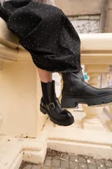 Botas negras de cuero sintético con hebilla lateral y suela track.