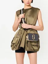 Bandolera Marc Jacobs modelo The Snapshot, de cuero color gris con detalles en beige y herrajes dorados. Presenta correa de tela con el logo de la marca y doble compartimento con cierre.