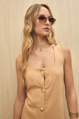 Vestido largo color beige, sin mangas, con escote cuadrado y abotonadura frontal completa. Corte recto con leve abertura en el ruedo.