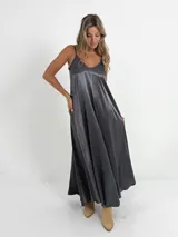 Vestido italiano amplio con escote en V, confeccionado en tela nacarada con cuerpo que aporta estructura y movimiento.