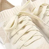 Zapatillas urbanas de mujer color beige, con capellada de tejido textil y suela blanca de PVC. Diseño con cordones a tono y tirador en el talón.