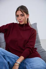 Sweater de punto color bordó, con cuello alto, mangas largas y aberturas laterales en el dobladillo.