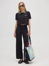 Pantalón negro de algodón, corte holgado y pierna ancha con pretina elástica. Presenta rayas blancas y celestes a los costados.