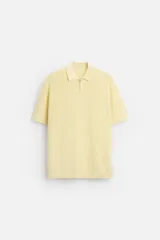 Polo color amarillo claro de punto perlado, corte regular, con cuello solapa y cierre frontal de cremallera.