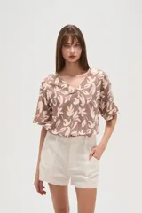 Blusa marrón con estampado de hojas color crema, cuello en V y mangas cortas. Corte holgado.