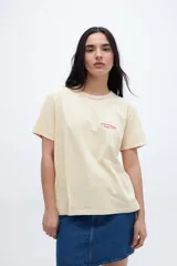 Remera color crema con estampado pequeño en el pecho con la leyenda "UNFRM. Redefining Energy Club".