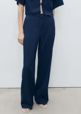 Pantalón largo azul marino de tiro alto y corte recto, confeccionado en tejido fluido 100% algodón. Presenta trabillas y cierre frontal con cremallera y botón.