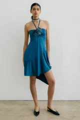 Vestido corto azul con escote halter, falda irregular y detalle de flor de lino con mostacillas en el escote.