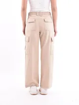 Pantalón cargo de mujer color beige claro, tiro medio/alto, corte ancho y recto, con bolsillos laterales tipo parche en las piernas.